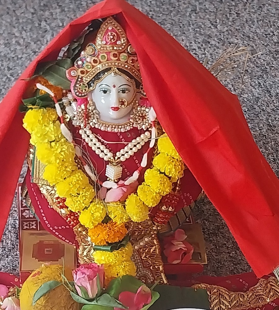 A Devi altar dressed with marigold garlands and offerings for a household puja