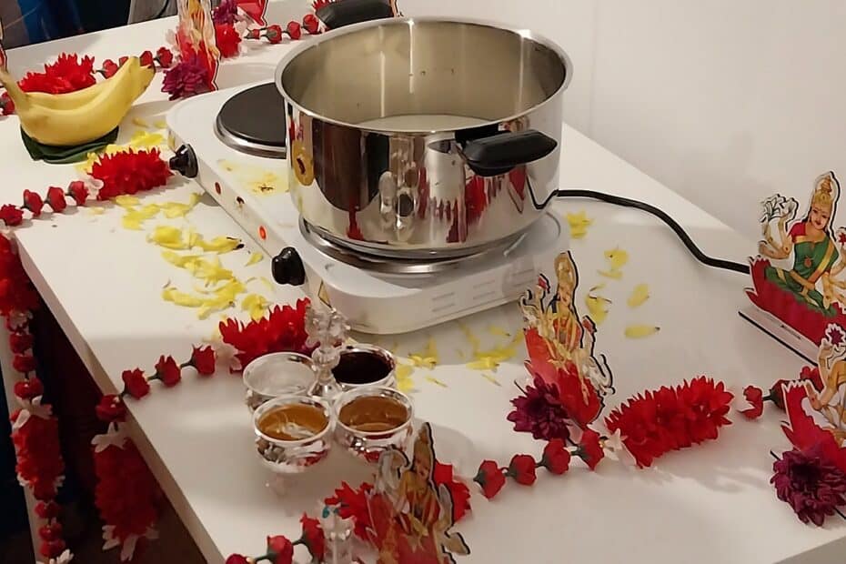 The milk set to boil on the altar during a Griha Pravesh, with garlands, offerings, and the image of Lakshmi