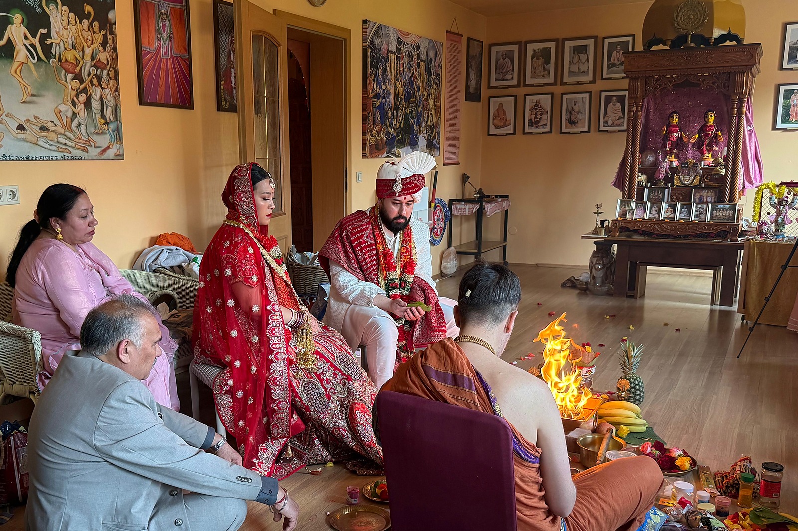 A Hindu wedding conducted before the temple altar with the lineage portraits behind