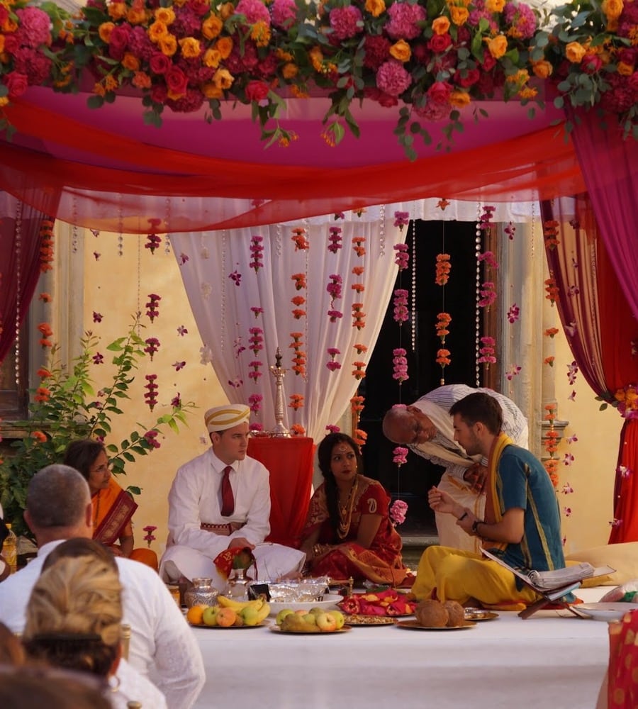 Bride and groom seated in the floral mandap during a Hindu wedding in Europe
