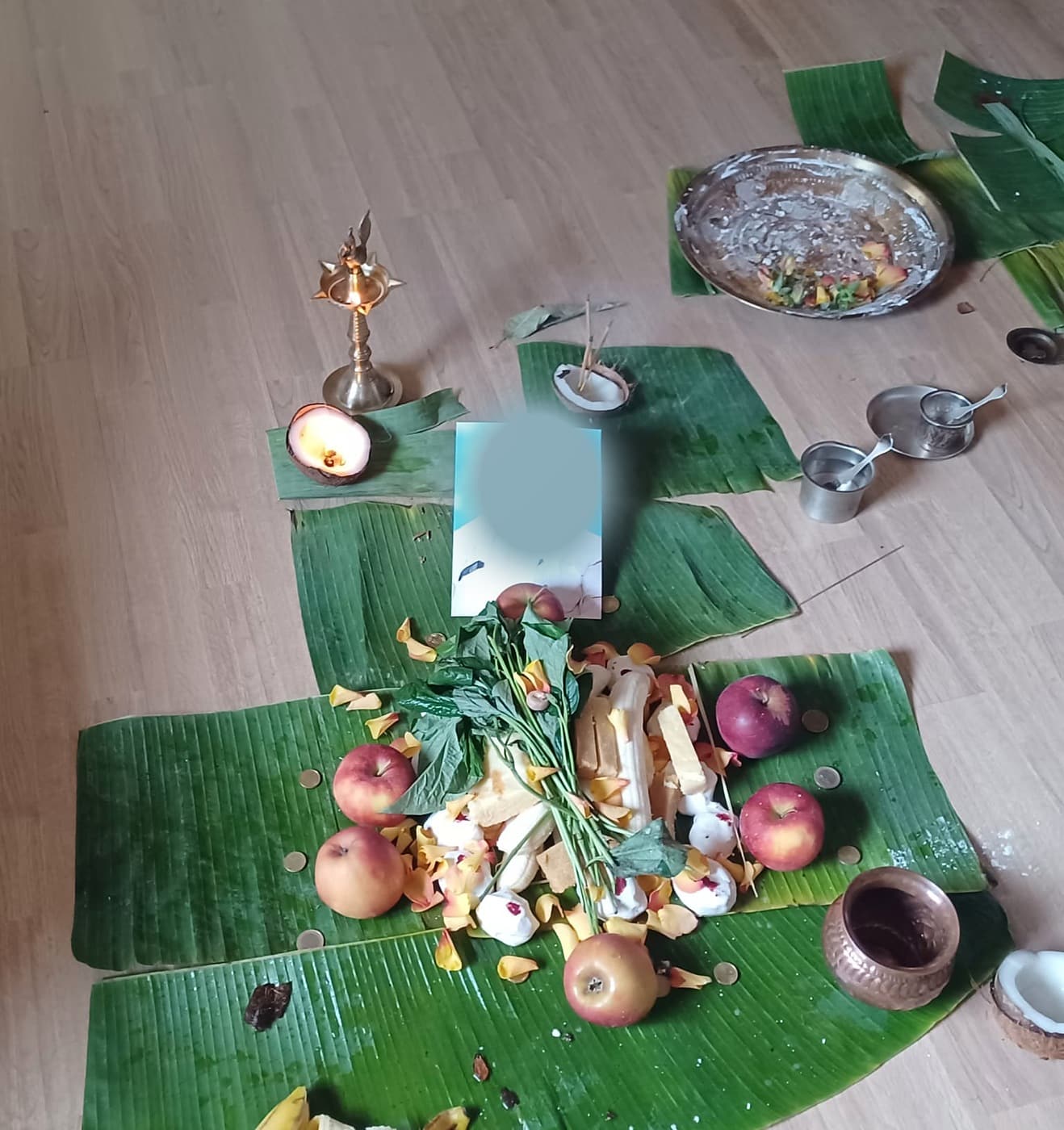 Offerings laid on banana leaves for a Pitru Puja, with rice pinda, fruit, flowers, lamp, and water vessel