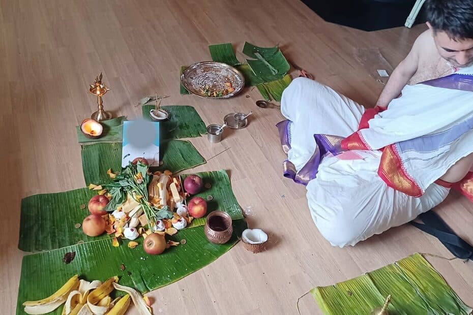 A priest seated at the ancestral offerings during a Pitru Puja conducted in a temple