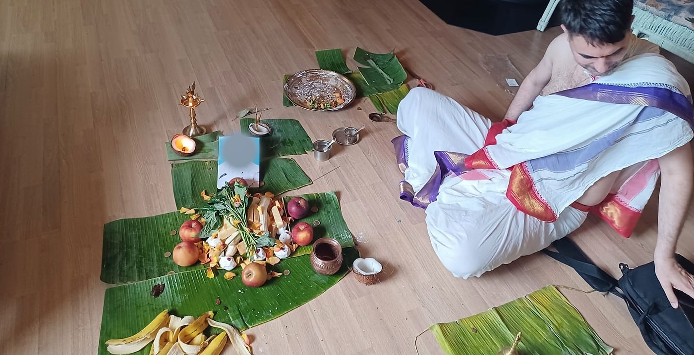 A priest seated at the ancestral offerings during a Pitru Puja conducted in a European home